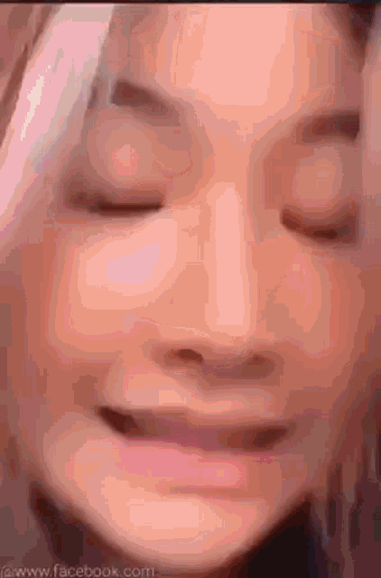 a close up of a woman 's face with her eyes closed and a smile on her face .