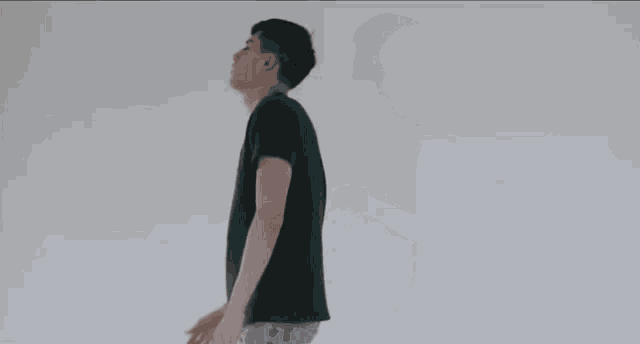 a young man in a green t-shirt is standing in front of a white wall