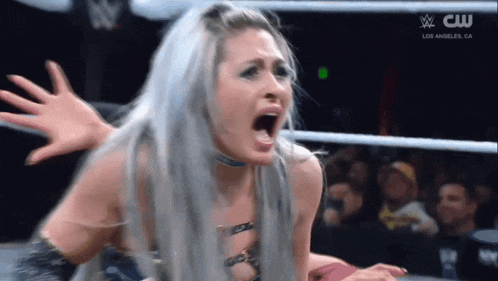 a woman is screaming in a wrestling ring with a cw logo in the background