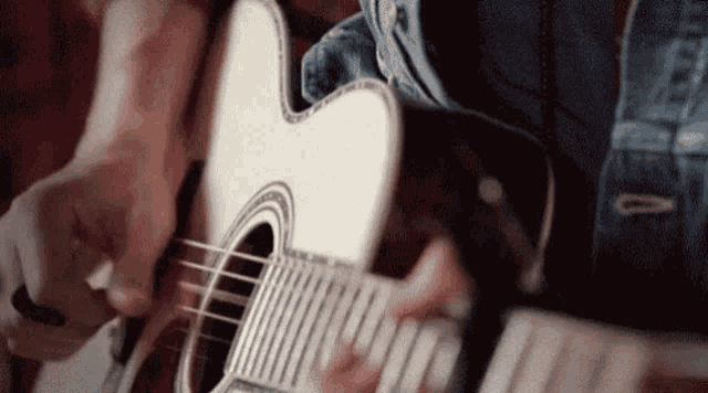 a close up of a person playing an acoustic guitar