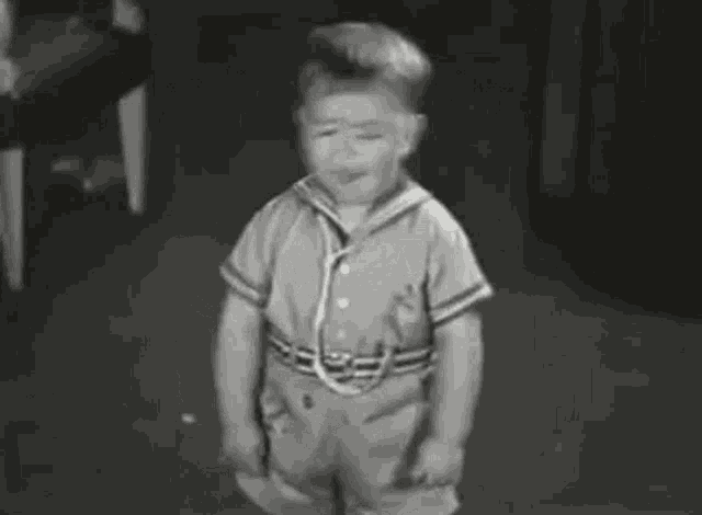 a black and white photo of a young boy dancing on the floor .