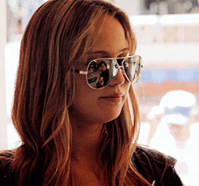 a woman wearing a pair of aviator sunglasses looks at something