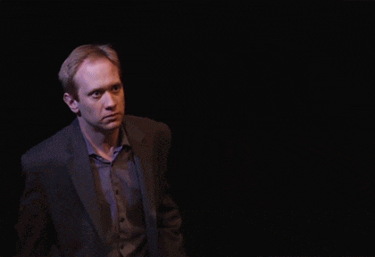 a man in a suit holds his fist up in the dark