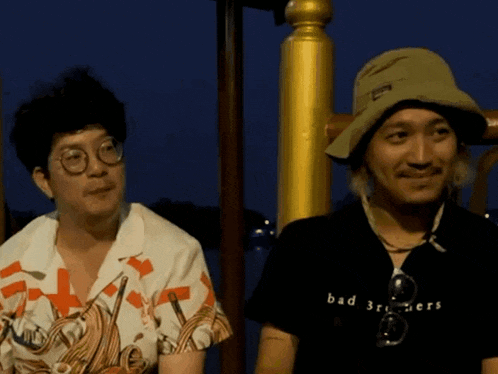 a man wearing a black shirt that says bad brothers sits next to another man