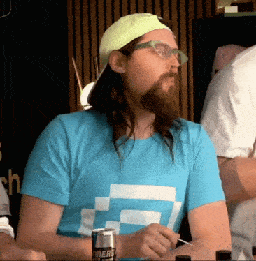 a man with long hair and a beard is wearing a blue shirt that says " merry " on it