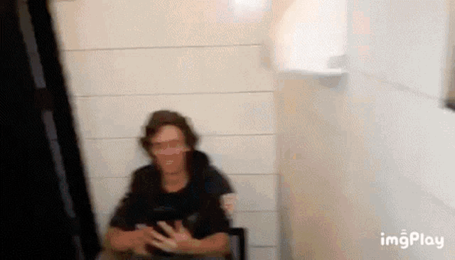 a man is sitting in a chair in front of a white wall in a room .