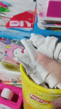 a person is holding a piece of cloth in a yellow bucket that says play dough