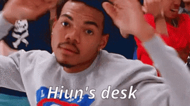 a man wearing a sweater that says hiun 's desk