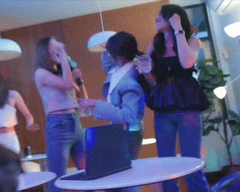 a group of people are standing around a table with a laptop on it