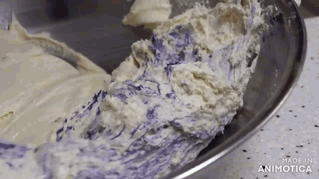 a close up of a bowl of frosting with purple swirls .