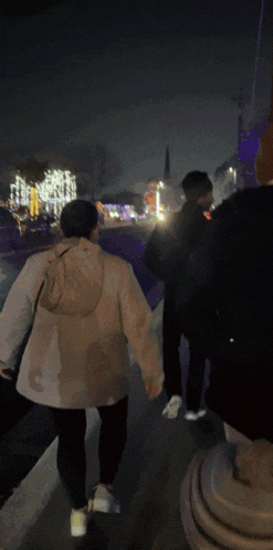 a person in a white jacket is walking down a sidewalk at night