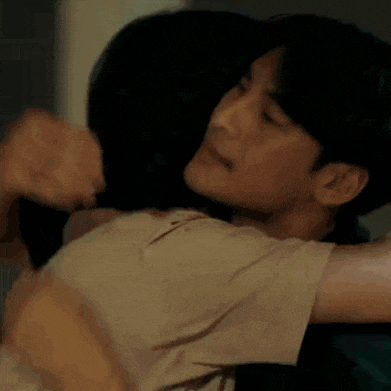 a man is touching a woman 's head while they are hugging each other .