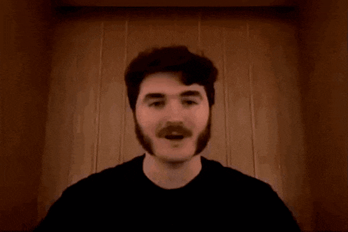 a man with a mustache giving a thumbs up