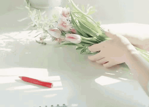 a woman is arranging a bouquet of flowers in a vase .