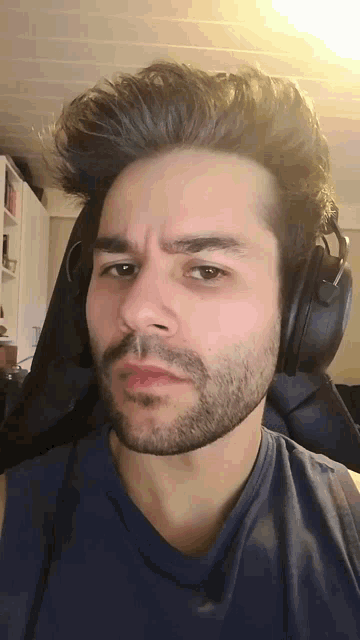 a man with a beard wearing headphones and a blue shirt