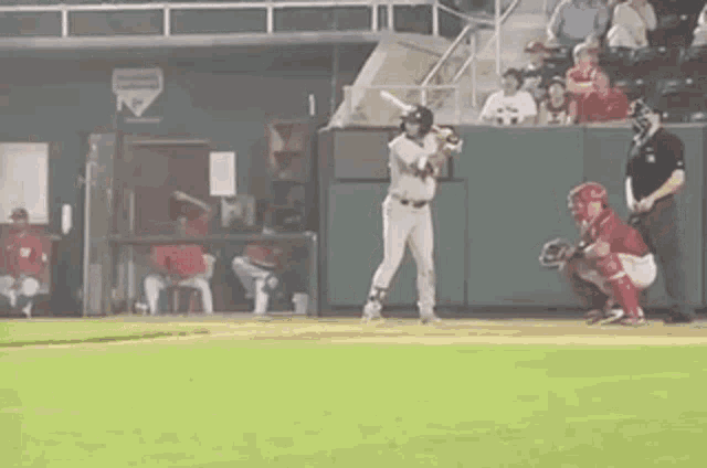 a baseball player is swinging a bat at a pitch while a catcher watches .