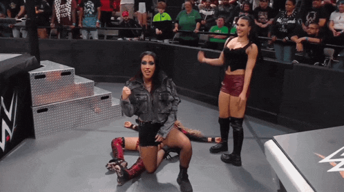a female wrestler is kneeling down in front of a sign that says nz
