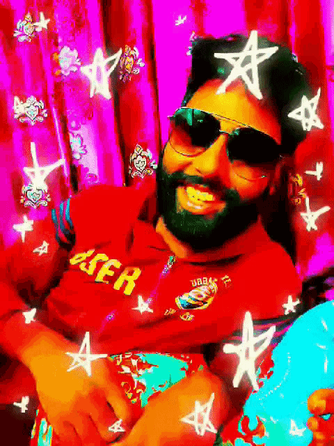a man with a beard wearing sunglasses and a red jacket that says laser on it