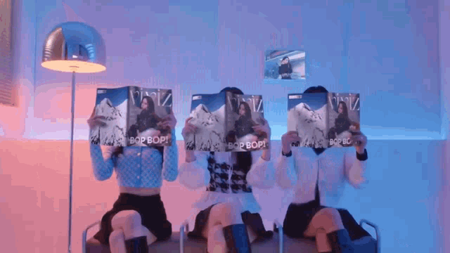three women are covering their faces with magazines that say bop bop