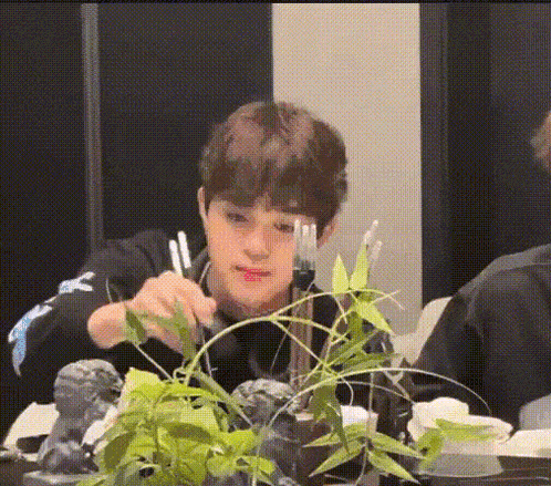 a young man is sitting at a table holding a fork and a knife .