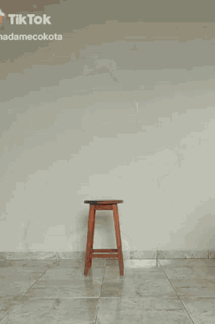 a woman in a red bodysuit and black boots is walking on a tiled floor .