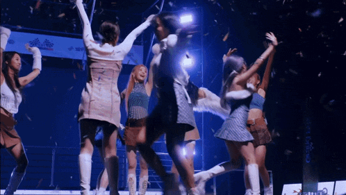a group of girls are dancing on a stage with confetti falling around them
