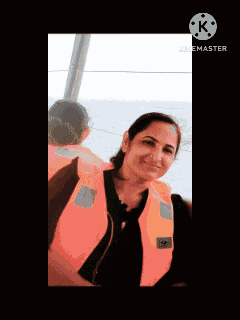 a woman wearing an orange life vest is smiling in a video taken by kinemaster