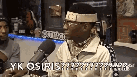 a man wearing a gucci headband is sitting in front of a microphone .