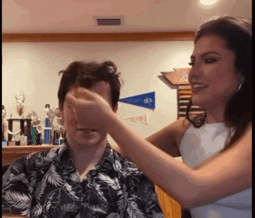 a woman wipes a man 's face with her hand in front of a sign that says ' athletic '