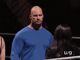 a man in a blue sweater is talking to a woman in a ring .
