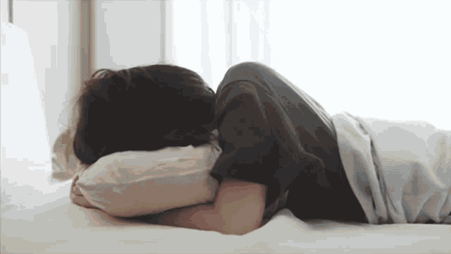 a person is laying on a bed with their head on a pillow .