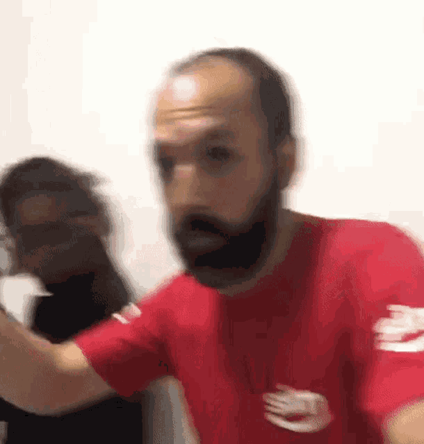 a blurry picture of a man with a beard wearing a red t-shirt with a hand on it