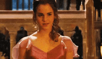 a woman in a pink dress is standing in a room with people .