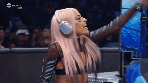 a woman wearing headphones is standing in a ring with her arms outstretched .