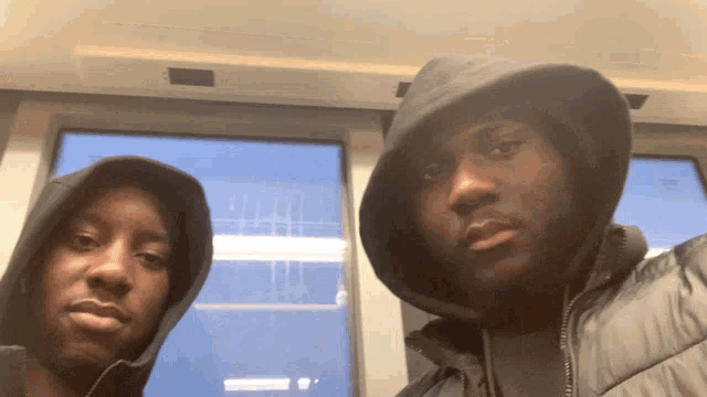 two men wearing hoodies are posing for a photo