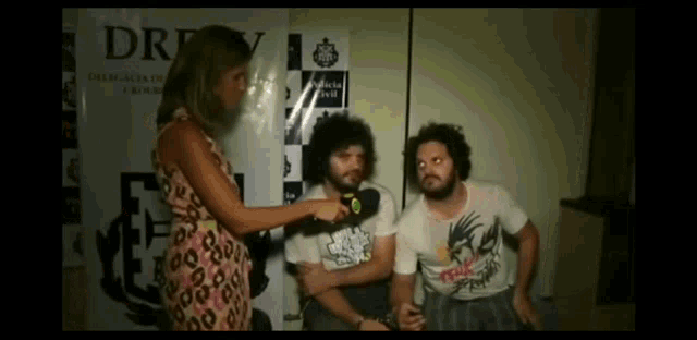 a woman interviews two men in front of a sign that says dr