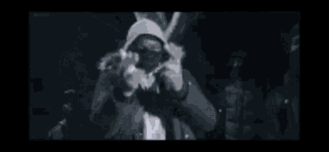 a group of people are standing in a dark room making signs with their hands .