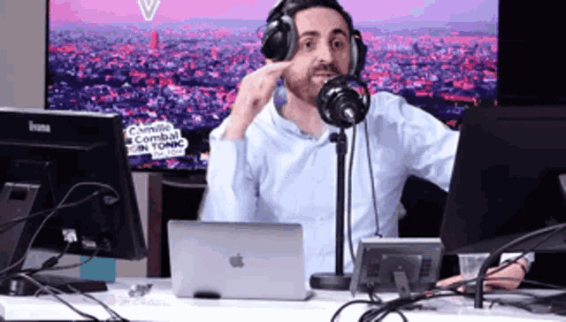 a man wearing headphones is sitting in front of a microphone and a laptop