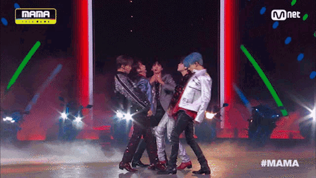 a group of men are dancing on a stage in front of a mnet logo