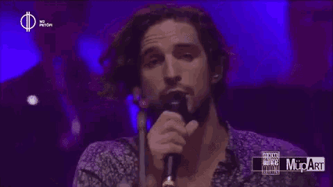 a man singing into a microphone with a purple background that says mupart on it