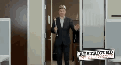 a man in a suit and crown is holding a cane in front of a sign that says restricted intelligence .
