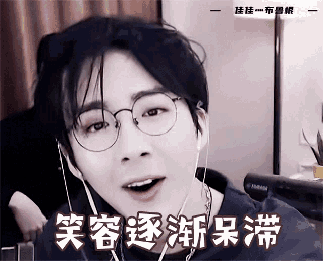 a man wearing glasses and ear buds has chinese writing on his shirt