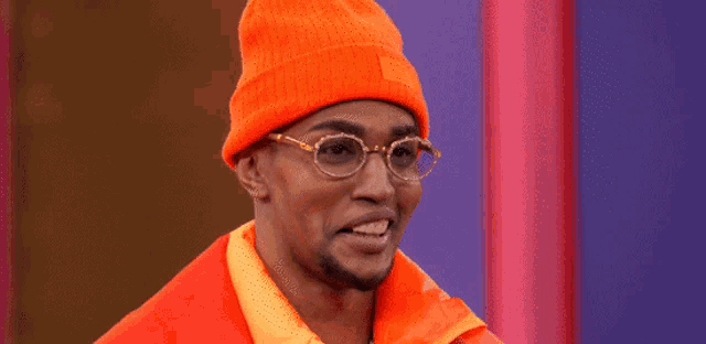 a man wearing a beanie and glasses is smiling