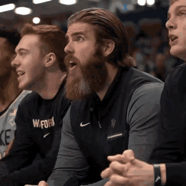 a man with a beard wearing a black nike shirt