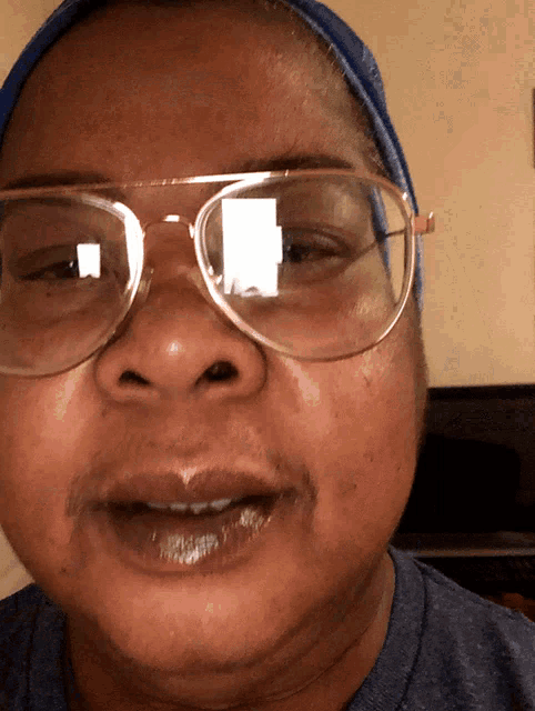 a close up of a person wearing glasses and a blue head scarf