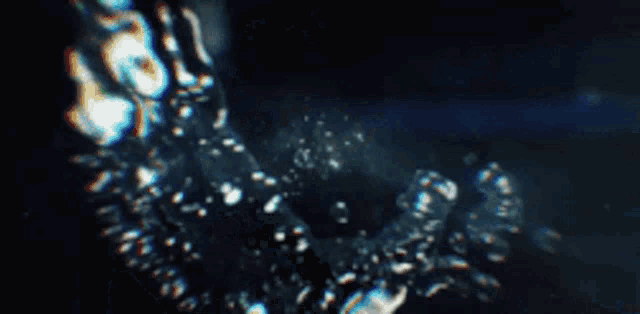 a blurred image of a person swimming in the water with bubbles coming out of the water .