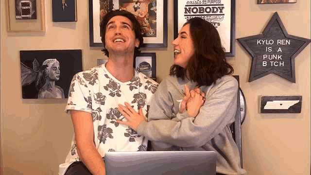 a man and woman are laughing in front of a sign that says kylo ren is a punk btch