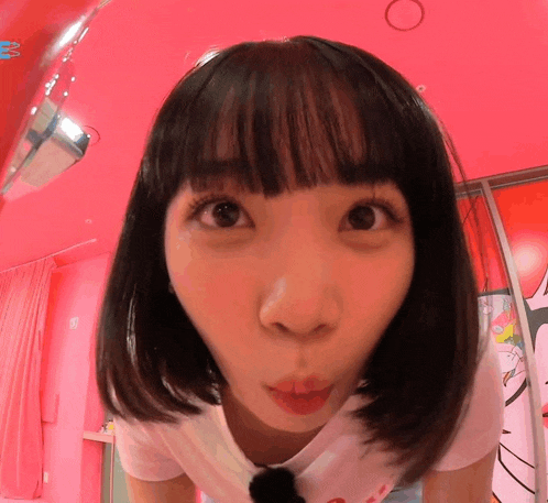 a close up of a woman 's face in a pink room