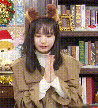 a young girl wearing a reindeer headband is praying in front of a bookshelf .