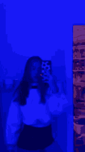 a girl is taking a selfie in front of a mirror in a room with blue lights .